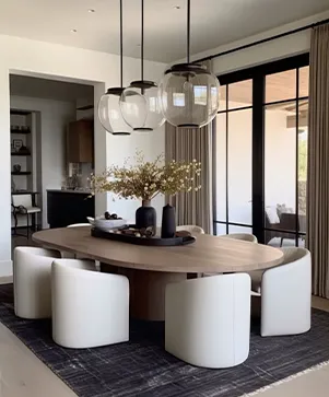 Modern luxury dining room setup at M3M Golfestate Gurgaon with oval wooden dining table white bucket chairs and glass globe pendant lights