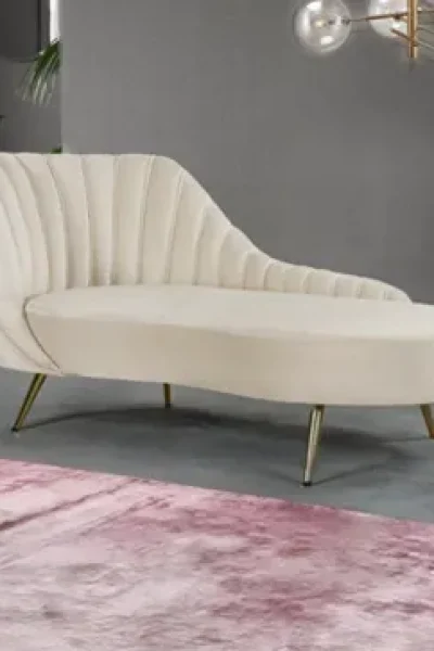 Custom cream velvet chaise lounge chair with brass legs in a modern luxury apartment living room at M3M Golfestate